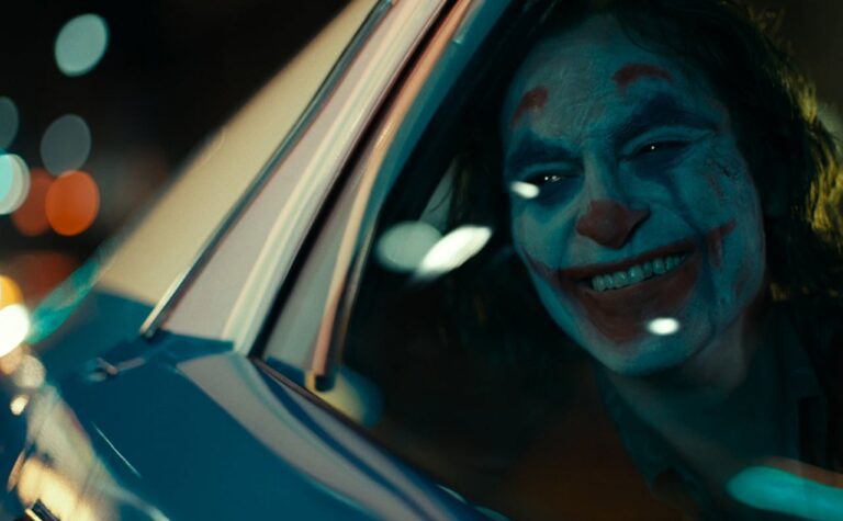joaquin phoenix sorridente dentro l'auto in una scena di joker