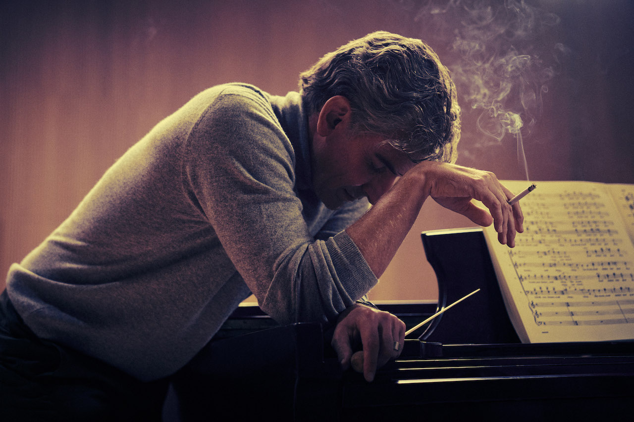 Bradley Cooper appoggiato al pianoforte in Maestro