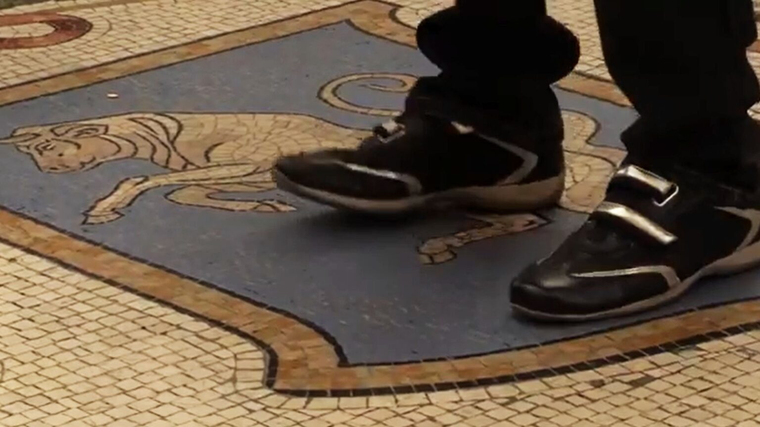 turista che fa rito sul toro della galleria di Milano
